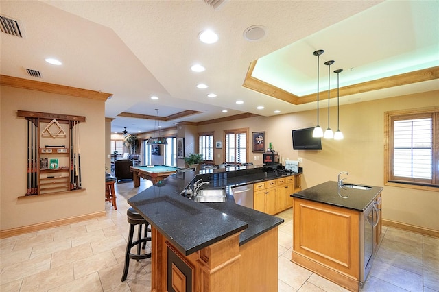 kitchen featuring sink, billiards, an island with sink, a tray ceiling, and decorative light fixtures