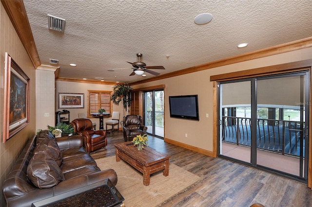 living room with a textured ceiling, hardwood / wood-style flooring, ceiling fan, and ornamental molding