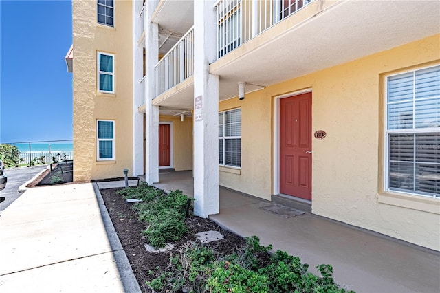 view of exterior entry featuring a balcony and a water view