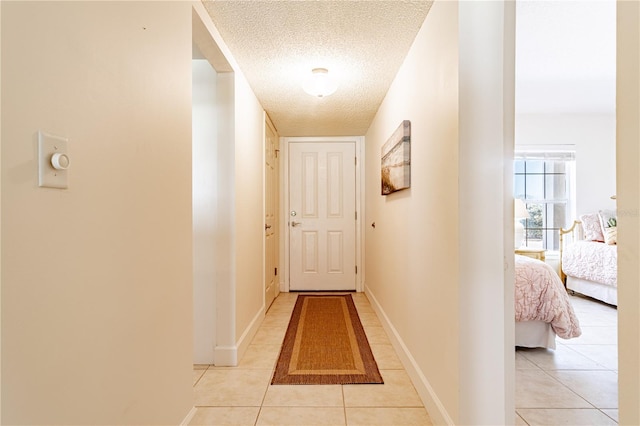 hall featuring light tile patterned floors and a textured ceiling