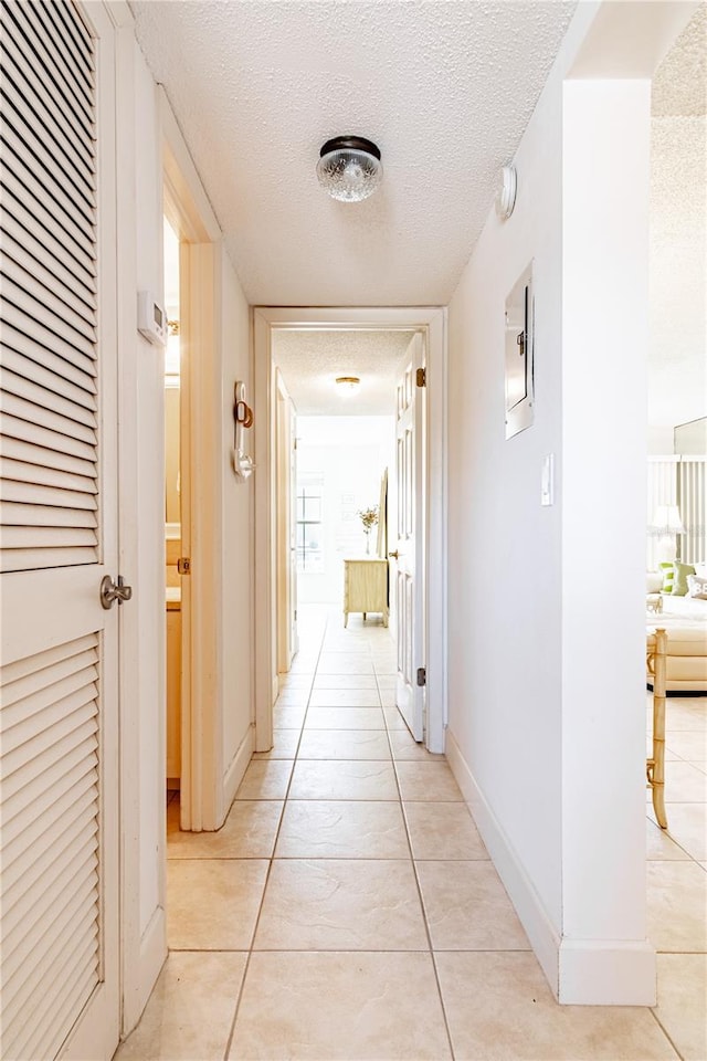 hall featuring a textured ceiling, a wealth of natural light, and light tile patterned flooring