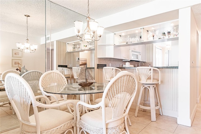 tiled dining space with a chandelier and a textured ceiling