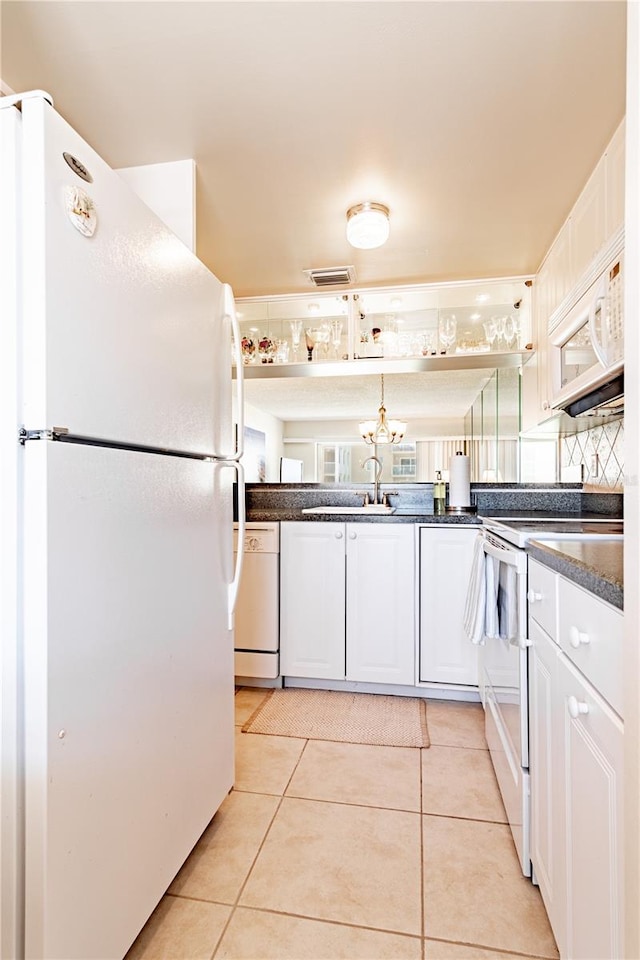 kitchen with white appliances, backsplash, sink, light tile patterned floors, and white cabinetry