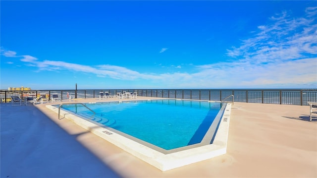 view of swimming pool featuring a water view and a patio