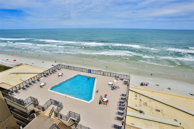 view of swimming pool featuring a view of the beach and a water view