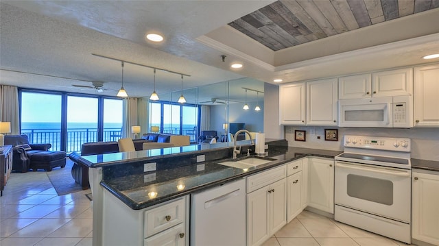 kitchen featuring kitchen peninsula, white appliances, a water view, and sink