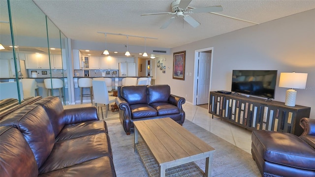 tiled living room featuring ceiling fan, track lighting, and a textured ceiling