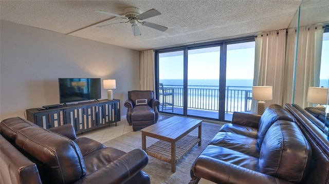 living room featuring ceiling fan, floor to ceiling windows, light tile patterned floors, and a textured ceiling