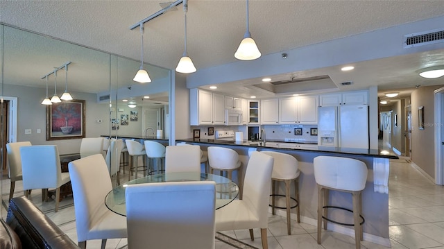 kitchen featuring pendant lighting, white cabinetry, white appliances, and a textured ceiling