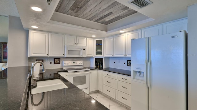 kitchen with white cabinetry, sink, white appliances, a tray ceiling, and light tile patterned flooring