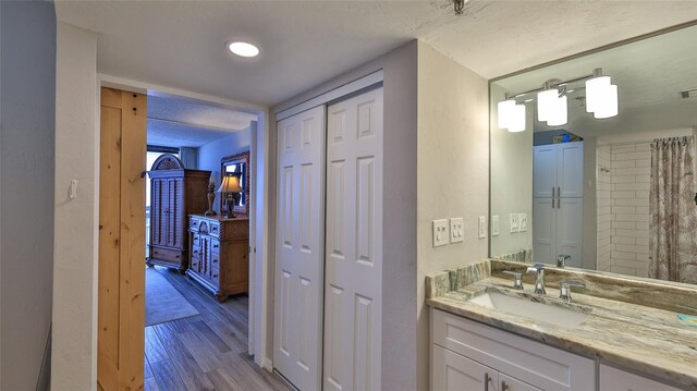 bathroom with hardwood / wood-style floors, vanity, and a textured ceiling