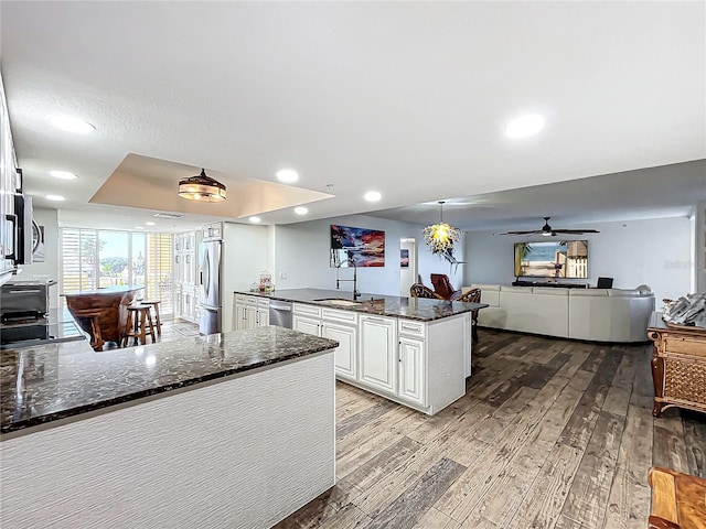 kitchen with white cabinetry, sink, light hardwood / wood-style flooring, dark stone countertops, and appliances with stainless steel finishes