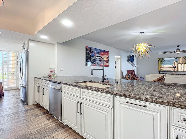 kitchen featuring dark hardwood / wood-style flooring, a textured ceiling, stainless steel appliances, sink, and decorative light fixtures