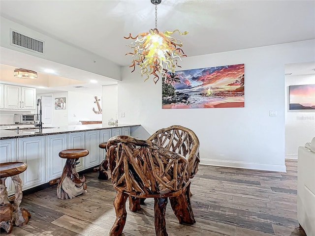 dining area with sink, dark hardwood / wood-style floors, and an inviting chandelier