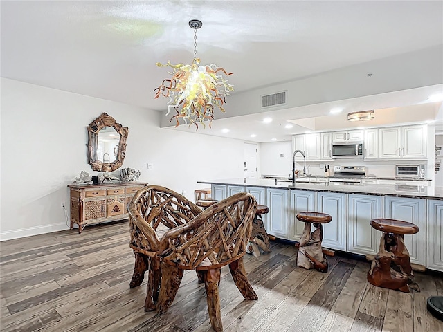 dining space with sink, dark hardwood / wood-style flooring, and an inviting chandelier