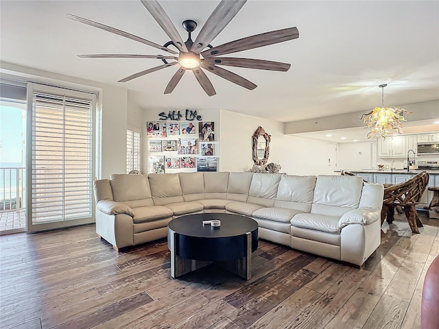 living room with ceiling fan with notable chandelier, hardwood / wood-style flooring, and sink