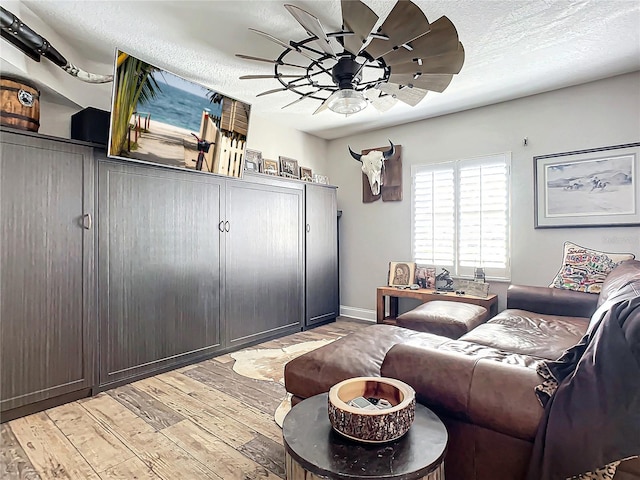 living room with a textured ceiling, light hardwood / wood-style flooring, and ceiling fan