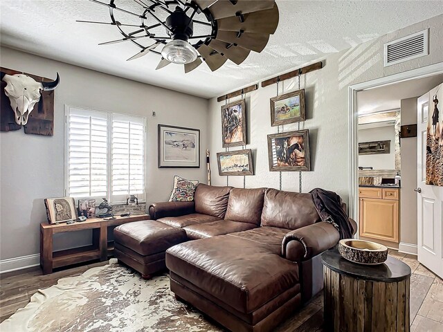 living room featuring hardwood / wood-style floors, a textured ceiling, and ceiling fan