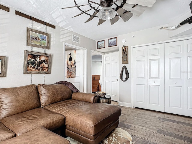 living room featuring hardwood / wood-style floors, a textured ceiling, and ceiling fan