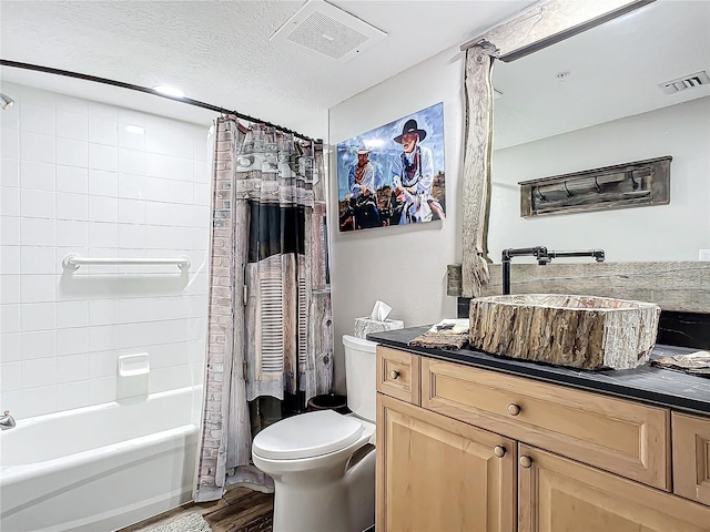 full bathroom featuring vanity, toilet, a textured ceiling, wood-type flooring, and shower / tub combo