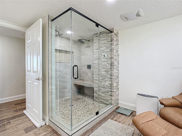 bathroom with a shower with door, a textured ceiling, and hardwood / wood-style flooring