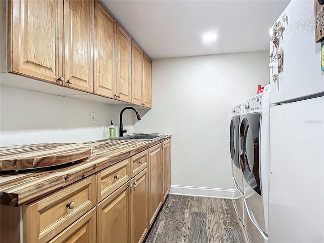 clothes washing area featuring cabinets, sink, dark hardwood / wood-style floors, and washing machine and clothes dryer