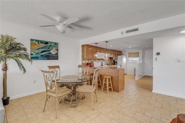 dining area with ceiling fan, light tile patterned flooring, and a textured ceiling