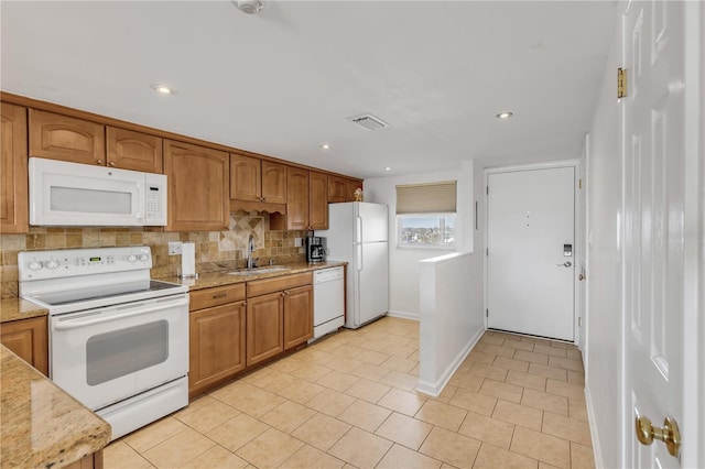 kitchen with decorative backsplash, sink, light stone counters, and white appliances