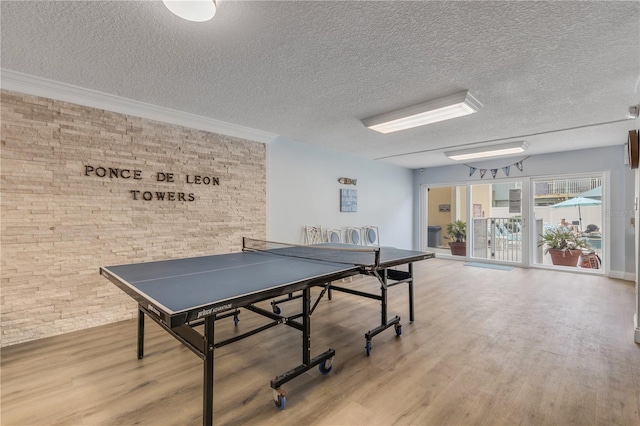 playroom with wood-type flooring, a textured ceiling, and ornamental molding