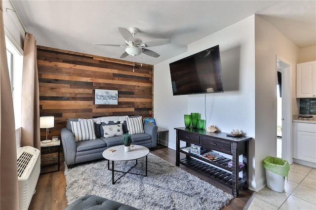 living room featuring ceiling fan, wood walls, a wealth of natural light, and light hardwood / wood-style flooring