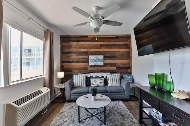 living room featuring ceiling fan, wood walls, dark hardwood / wood-style flooring, and a wall unit AC