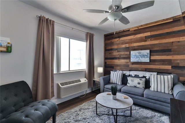 living room featuring ceiling fan, a wall mounted AC, dark wood-type flooring, and wood walls