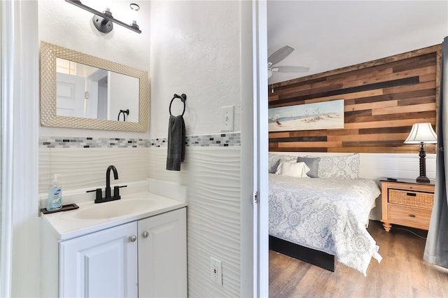 bathroom with ceiling fan, wooden walls, vanity, and hardwood / wood-style flooring