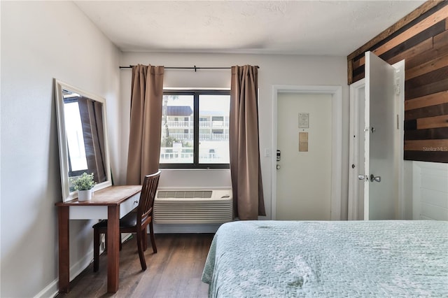 bedroom featuring dark hardwood / wood-style flooring and a wall mounted AC