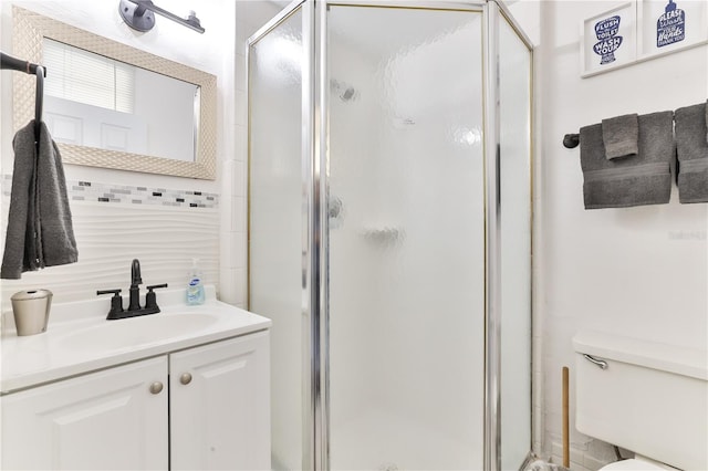 bathroom featuring a shower with door, vanity, and toilet