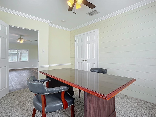 carpeted office space with crown molding, wooden walls, and ceiling fan