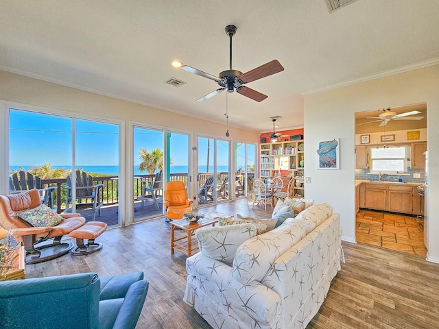 living room with ceiling fan, a wealth of natural light, a water view, and hardwood / wood-style flooring