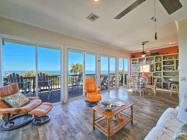 living room featuring ceiling fan, dark hardwood / wood-style floors, a water view, and a textured ceiling