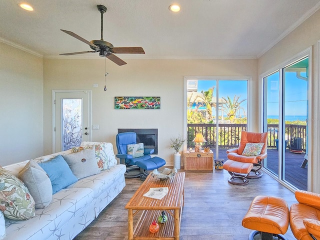 living room featuring wood-type flooring, ceiling fan, and crown molding