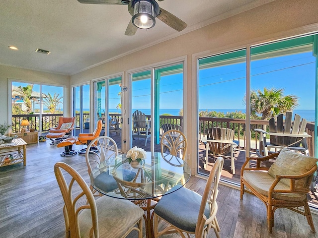 sunroom / solarium featuring a water view, plenty of natural light, and ceiling fan