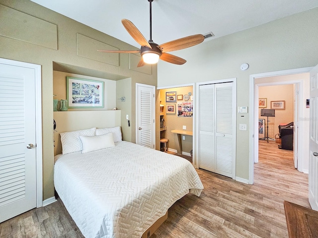 bedroom with light wood-type flooring, two closets, and ceiling fan