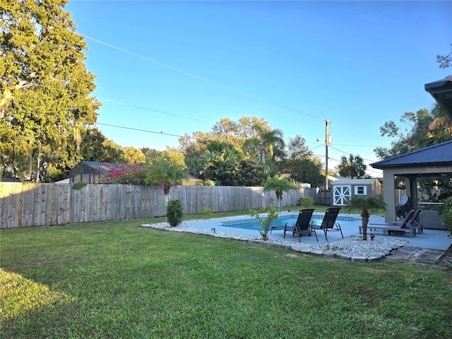 view of yard featuring a storage unit, a fenced in pool, and a patio