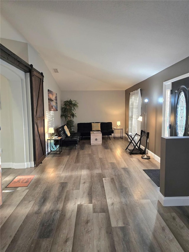 living room featuring a barn door, hardwood / wood-style floors, and lofted ceiling