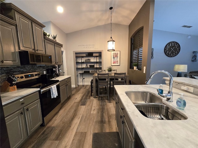 kitchen featuring sink, vaulted ceiling, decorative backsplash, appliances with stainless steel finishes, and dark hardwood / wood-style flooring