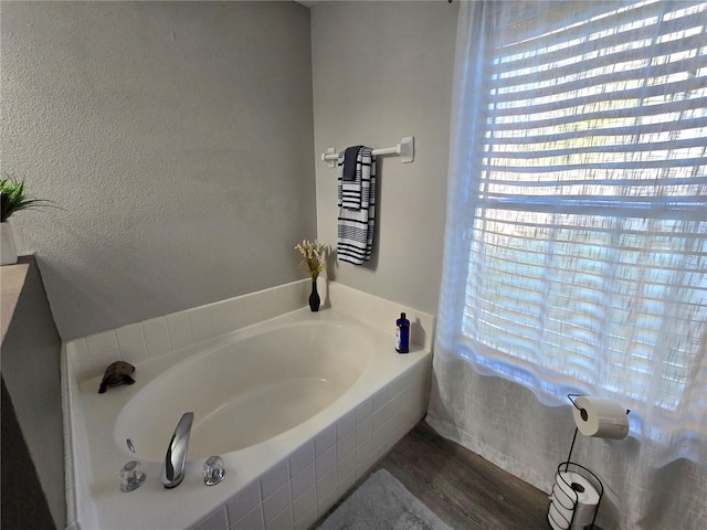 bathroom with hardwood / wood-style flooring and tiled tub