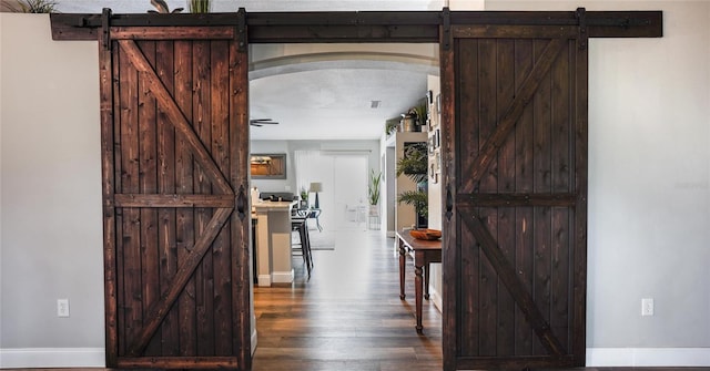 corridor featuring a textured ceiling, a barn door, and dark hardwood / wood-style floors