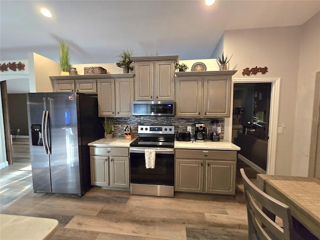 kitchen featuring backsplash, gray cabinetry, stainless steel appliances, and light hardwood / wood-style flooring