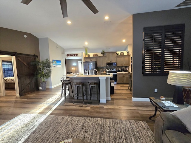 interior space featuring a barn door, ceiling fan, dark hardwood / wood-style flooring, and vaulted ceiling