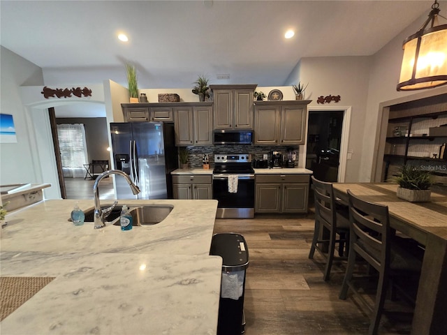 kitchen with appliances with stainless steel finishes, dark wood-type flooring, sink, pendant lighting, and gray cabinets