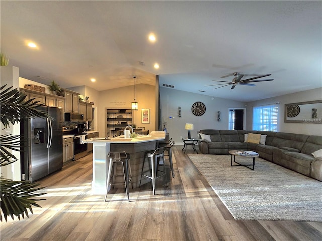 kitchen featuring a breakfast bar, lofted ceiling, an island with sink, light hardwood / wood-style floors, and stainless steel appliances